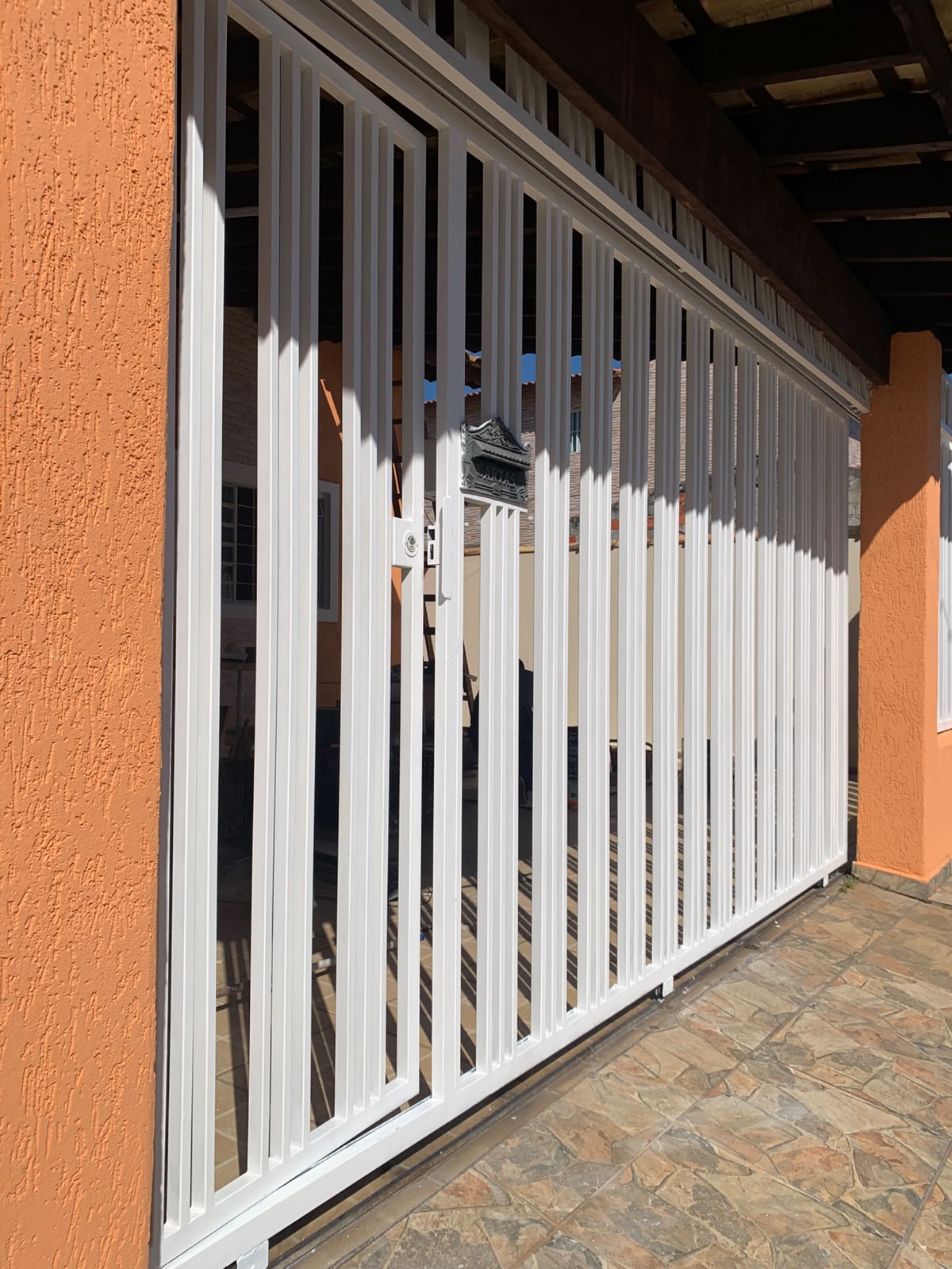 Portão e grade pintados em branco com parede externa laranja